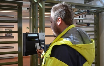 A man scanning his security pass at a gate