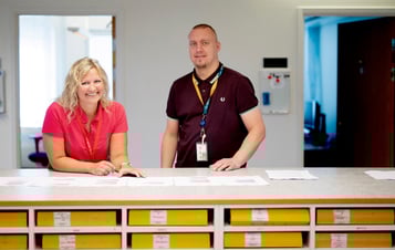 Två medarbetare på Ringhals bakom en lång disk med pärmar och papper.