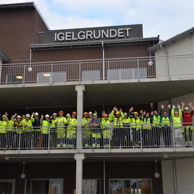 En grupp glada medarbetare på Forsmark vinkar från personalboendet Igelgrundet En grupp glada medarbetare på Forsmark vinkar från personalboendet Igelgrundet